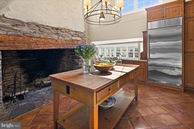 interior space featuring a towering ceiling, an inviting chandelier, pendant lighting, and built in fridge