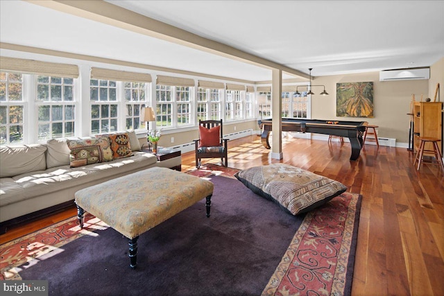 living room with an AC wall unit, hardwood / wood-style floors, a baseboard heating unit, and a healthy amount of sunlight