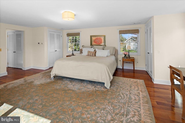 bedroom featuring two closets and dark hardwood / wood-style floors