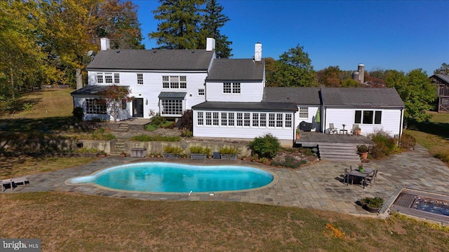 rear view of house featuring a swimming pool side deck, a patio, and a lawn