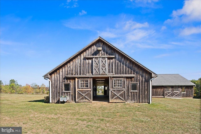 back of property featuring a lawn and an outbuilding