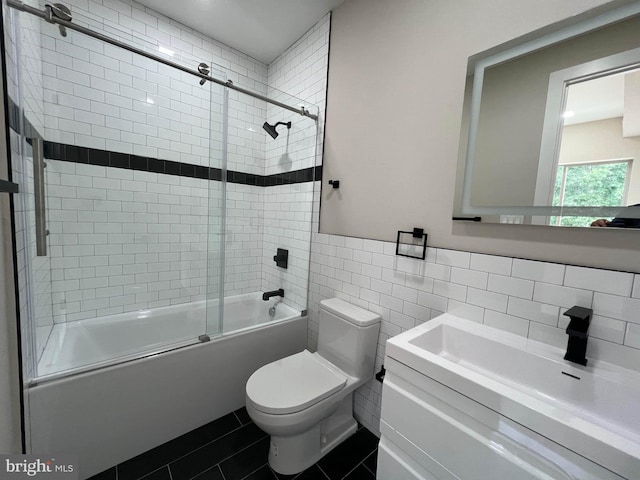 full bathroom with tile walls, tile patterned floors, vanity, enclosed tub / shower combo, and toilet