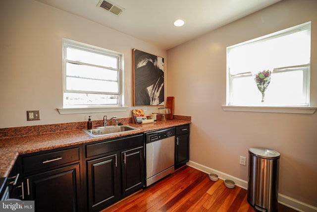 kitchen featuring dark hardwood / wood-style flooring, stainless steel dishwasher, dark stone counters, and sink