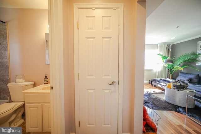 bathroom featuring vanity, crown molding, hardwood / wood-style floors, and toilet