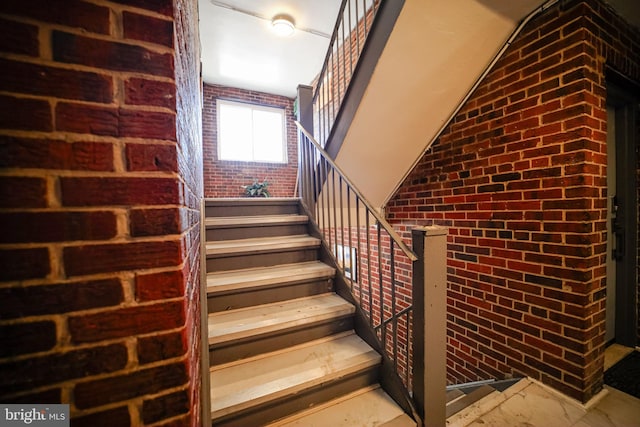 staircase featuring brick wall