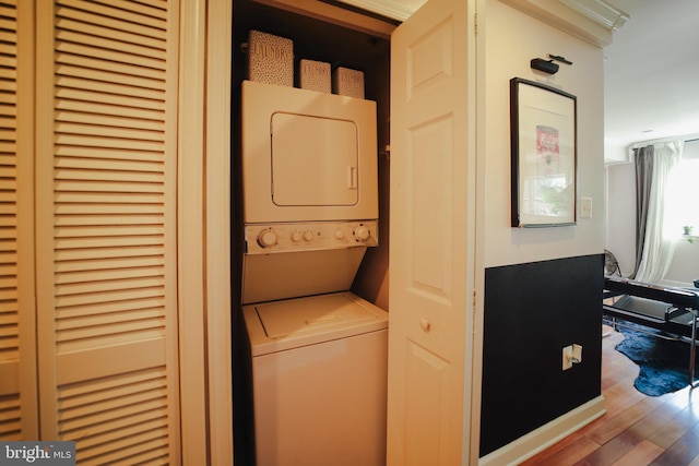 laundry area featuring wood-type flooring and stacked washer / drying machine