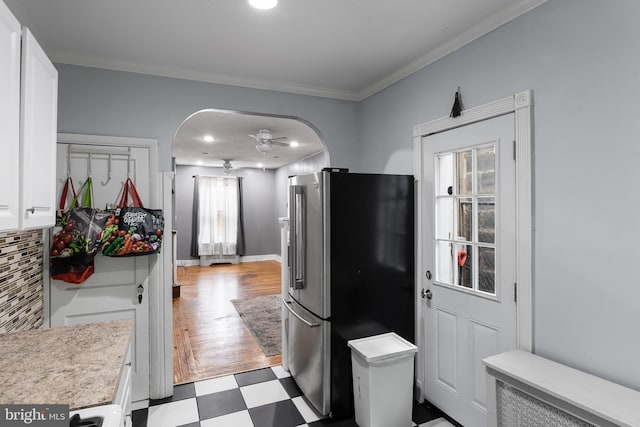 kitchen featuring high end refrigerator, tasteful backsplash, white cabinetry, ceiling fan, and crown molding