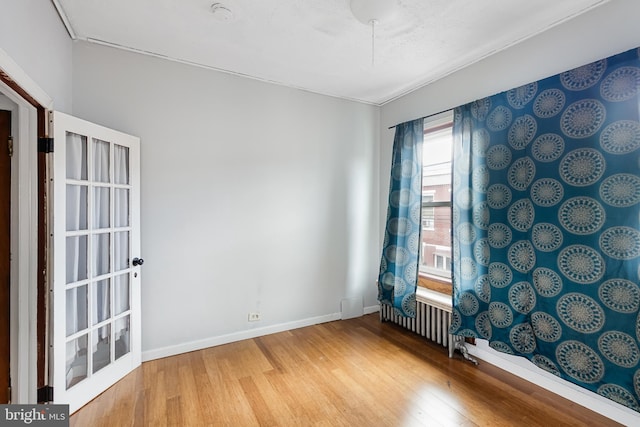 unfurnished room with radiator heating unit and wood-type flooring