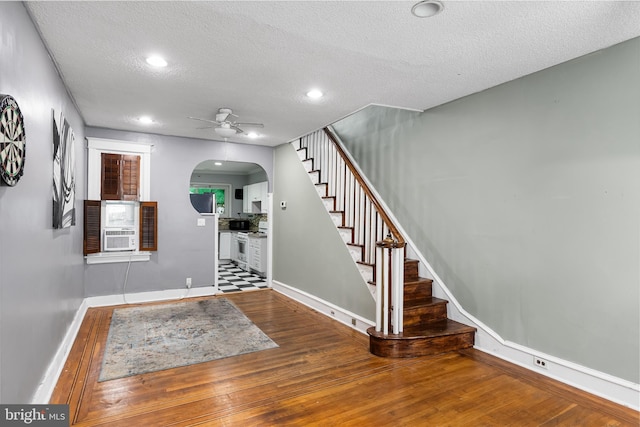 entryway with cooling unit, a textured ceiling, wood-type flooring, and ceiling fan