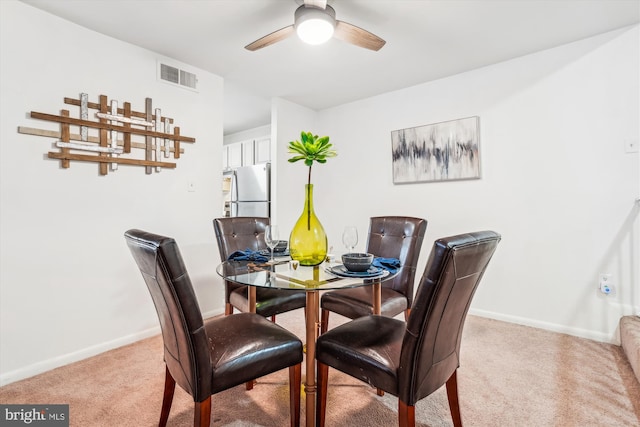 carpeted dining area with ceiling fan