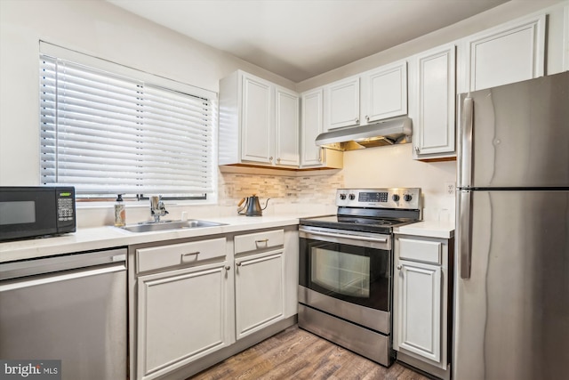 kitchen featuring wood-type flooring, appliances with stainless steel finishes, sink, and white cabinets