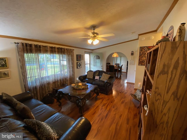 living room featuring ornamental molding, wood-type flooring, a textured ceiling, and ceiling fan