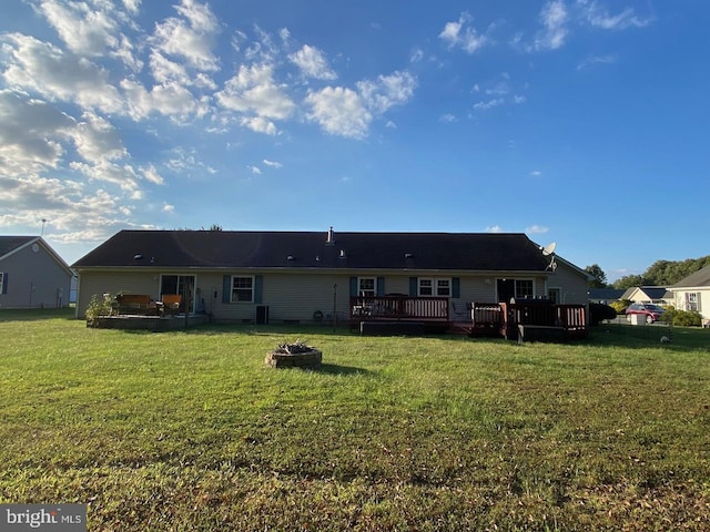 back of house with a fire pit, a wooden deck, and a yard