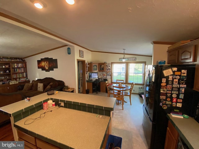 kitchen featuring crown molding, vaulted ceiling, wood-type flooring, and stainless steel fridge