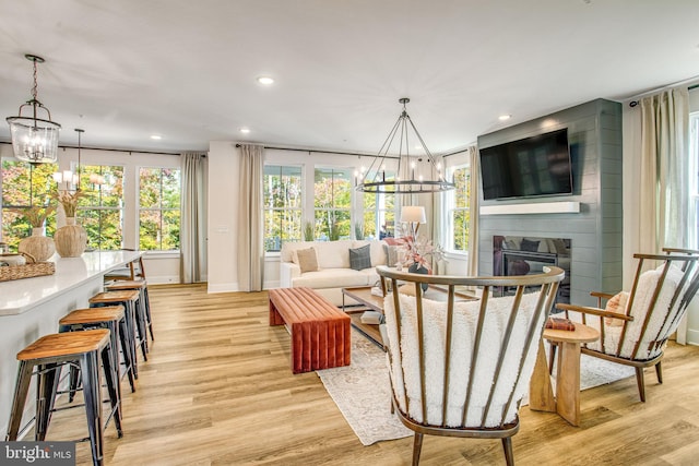 living room with a large fireplace, an inviting chandelier, light hardwood / wood-style floors, and a healthy amount of sunlight