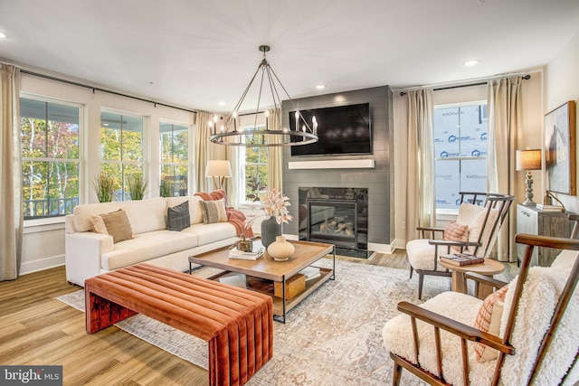 living room featuring a chandelier, light hardwood / wood-style flooring, and a large fireplace