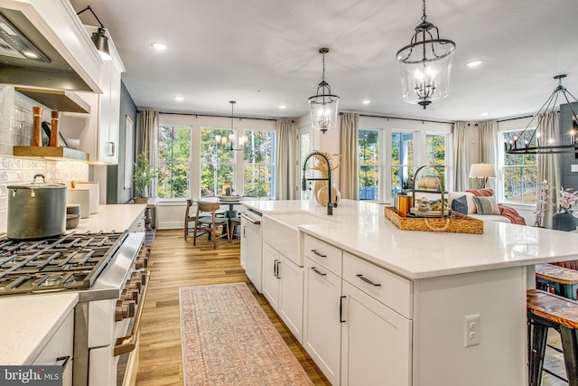 kitchen with a large island, decorative light fixtures, light wood-type flooring, and stainless steel appliances