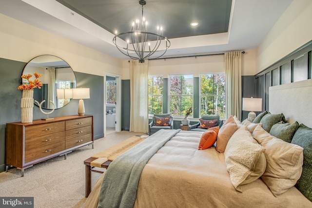 bedroom featuring light carpet, a tray ceiling, and an inviting chandelier