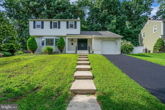 view of front of property featuring cooling unit, a garage, and a front lawn