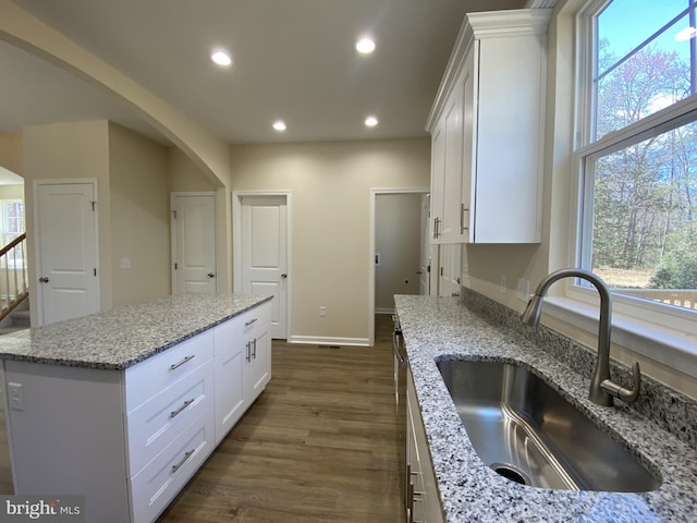 kitchen with light stone countertops, white cabinetry, recessed lighting, a sink, and dark wood-style floors