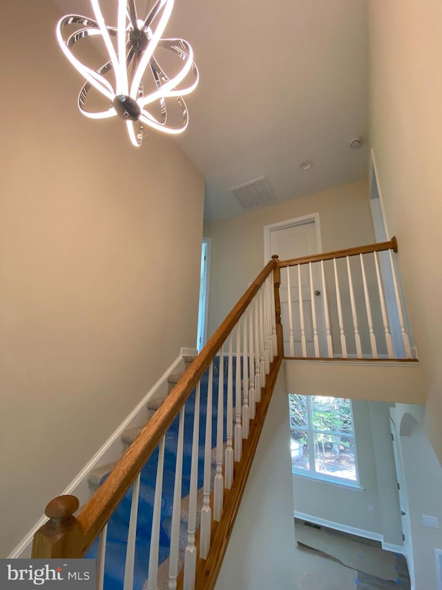 staircase featuring concrete floors and a notable chandelier