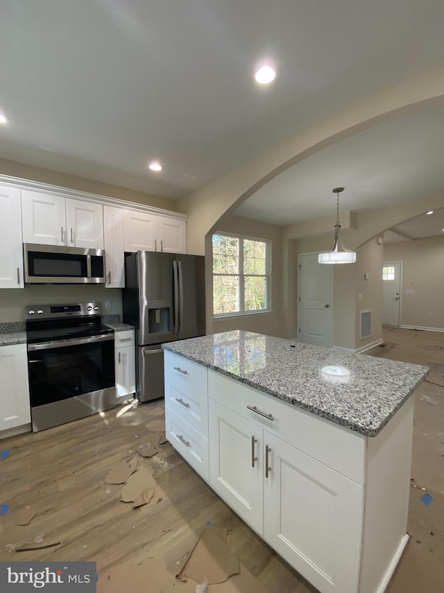 kitchen with light hardwood / wood-style floors, light stone counters, stainless steel appliances, hanging light fixtures, and white cabinetry