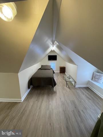 unfurnished bedroom featuring hardwood / wood-style flooring and vaulted ceiling with beams