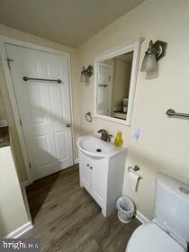 bathroom featuring vanity, wood-type flooring, and toilet