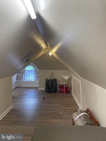 additional living space with dark wood-type flooring and vaulted ceiling