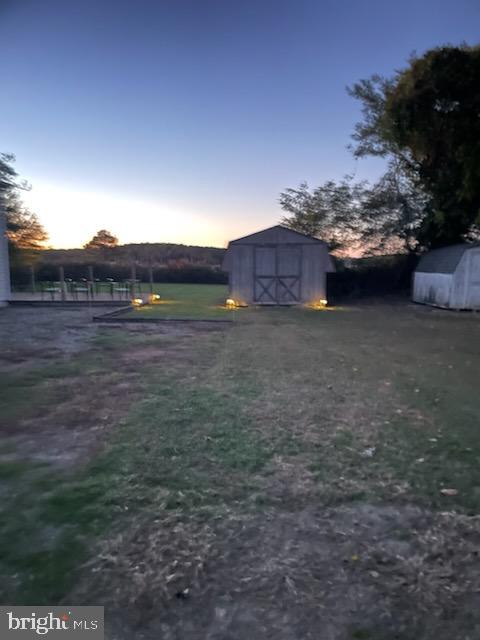 yard at dusk featuring a storage unit