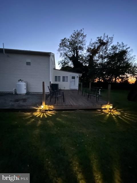 yard at dusk featuring a wooden deck