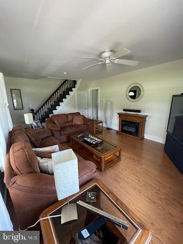 2826 Hoopers Island Rd, Church Creek, MD 21622 - living area with wood finished floors, a fireplace, baseboards, stairway, and a ceiling fan