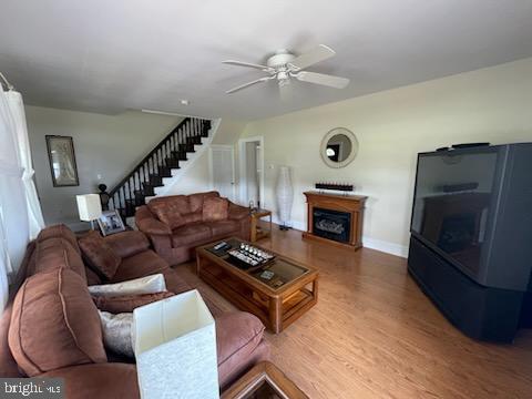 2826 Hoopers Island Rd, Church Creek, MD 21622 - living room with wood finished floors, a fireplace, baseboards, stairway, and a ceiling fan