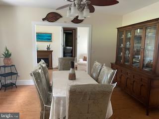 2826 Hoopers Island Rd, Church Creek, MD 21622 - dining space with baseboards, wood finished floors, a ceiling fan, and a fireplace