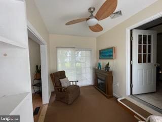 sitting room featuring a fireplace and ceiling fan