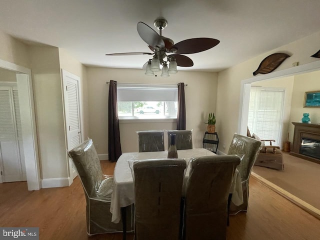 2826 Hoopers Island Rd, Church Creek, MD 21622 - dining space featuring ceiling fan, baseboards, light wood-style flooring, and a glass covered fireplace