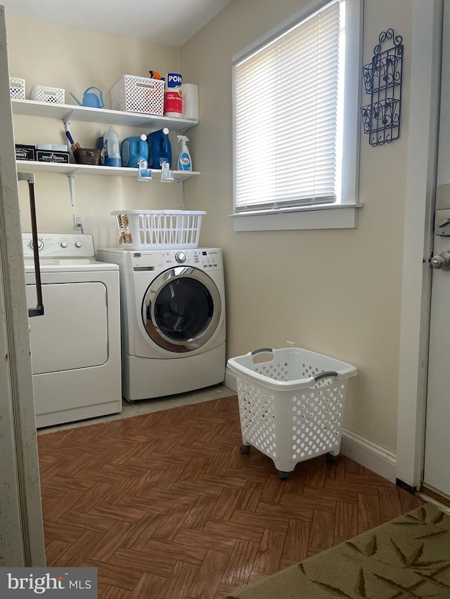 washroom with dark parquet floors and washer and clothes dryer