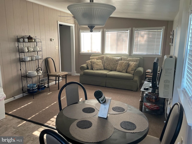 carpeted dining space with vaulted ceiling