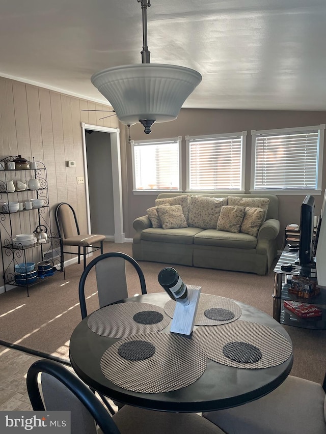 carpeted dining area with wood walls and lofted ceiling