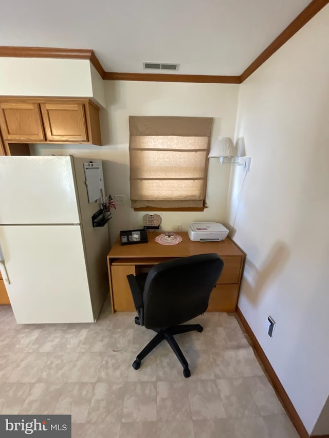 office space with built in desk and ornamental molding