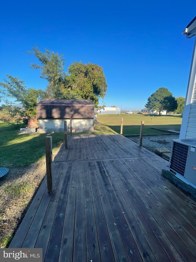 wooden deck featuring central air condition unit, an outdoor structure, and a yard