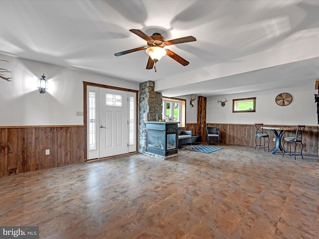 entryway featuring a fireplace, wooden walls, and ceiling fan