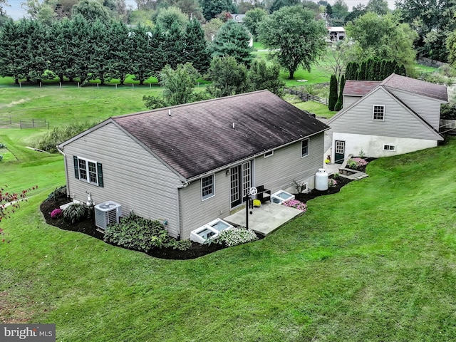 rear view of house featuring a patio, cooling unit, and a lawn