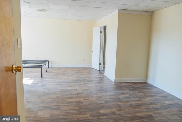 empty room featuring a drop ceiling and dark hardwood / wood-style floors