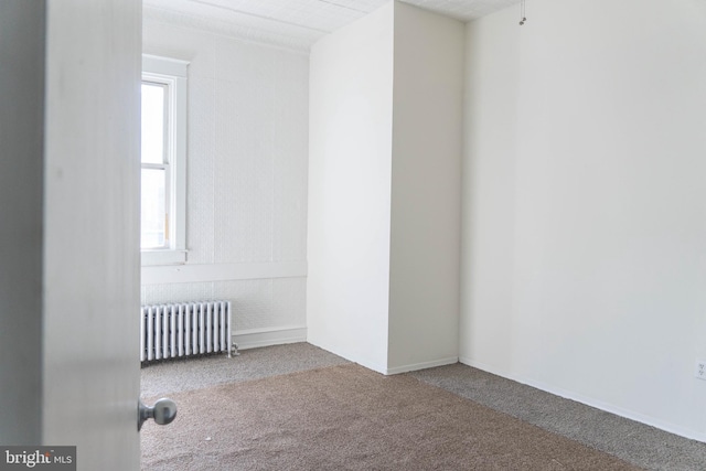 empty room featuring radiator heating unit and carpet floors