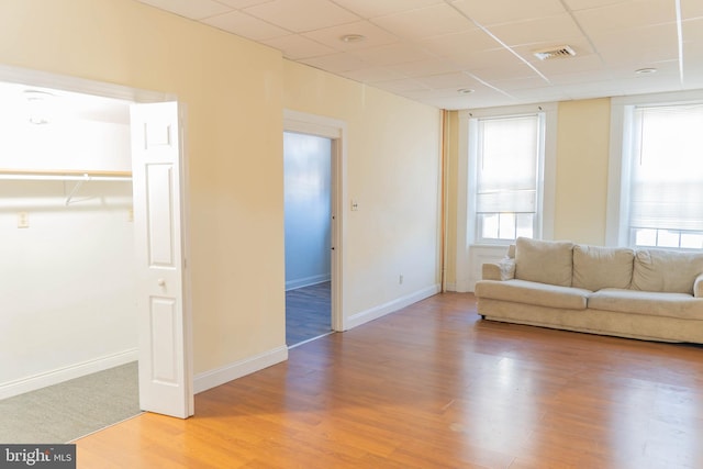 unfurnished living room featuring light hardwood / wood-style floors and a drop ceiling