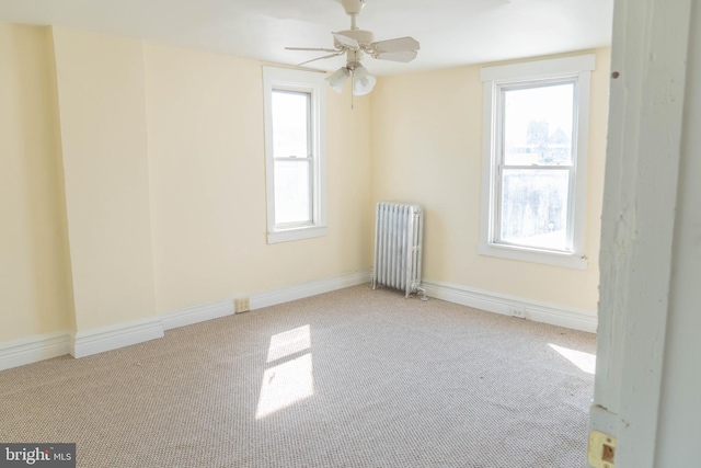 carpeted spare room with radiator and ceiling fan