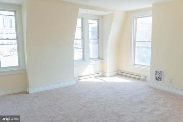 unfurnished room featuring light carpet, baseboard heating, and a wealth of natural light