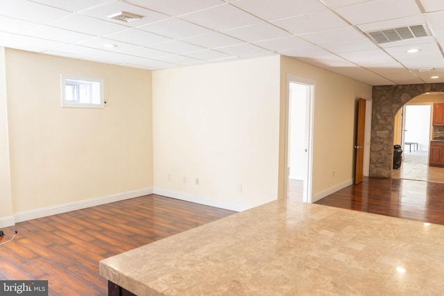 spare room with a drop ceiling and dark hardwood / wood-style flooring