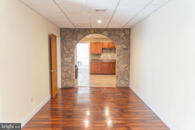 hallway with dark wood-type flooring and a drop ceiling